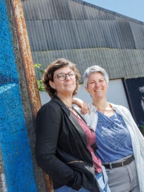 Émilie Adeline, la chargée de projets Coopération Citoyenne de la Ville de Blagnac, et Valérie Idrac, la directrice de la Glanerie, devant le hangar de la nouvelle ressourcerie du tiers-lieu Les Alouettes de Blagnac © Récit en Série – Patrice Nin.
